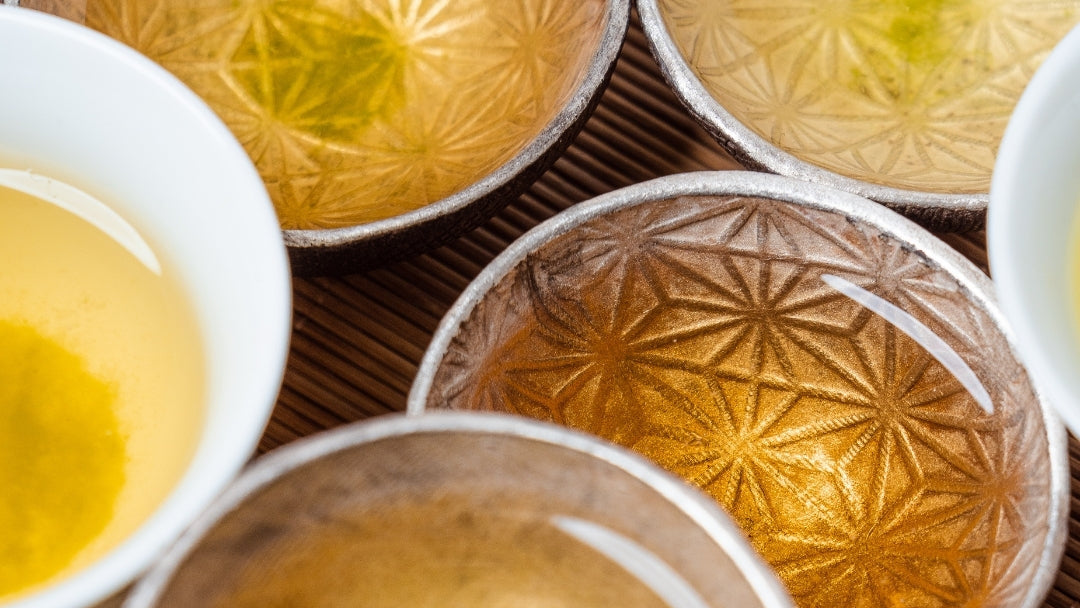 Close-up of ornate metal cups with intricate designs filled with Japanese tea