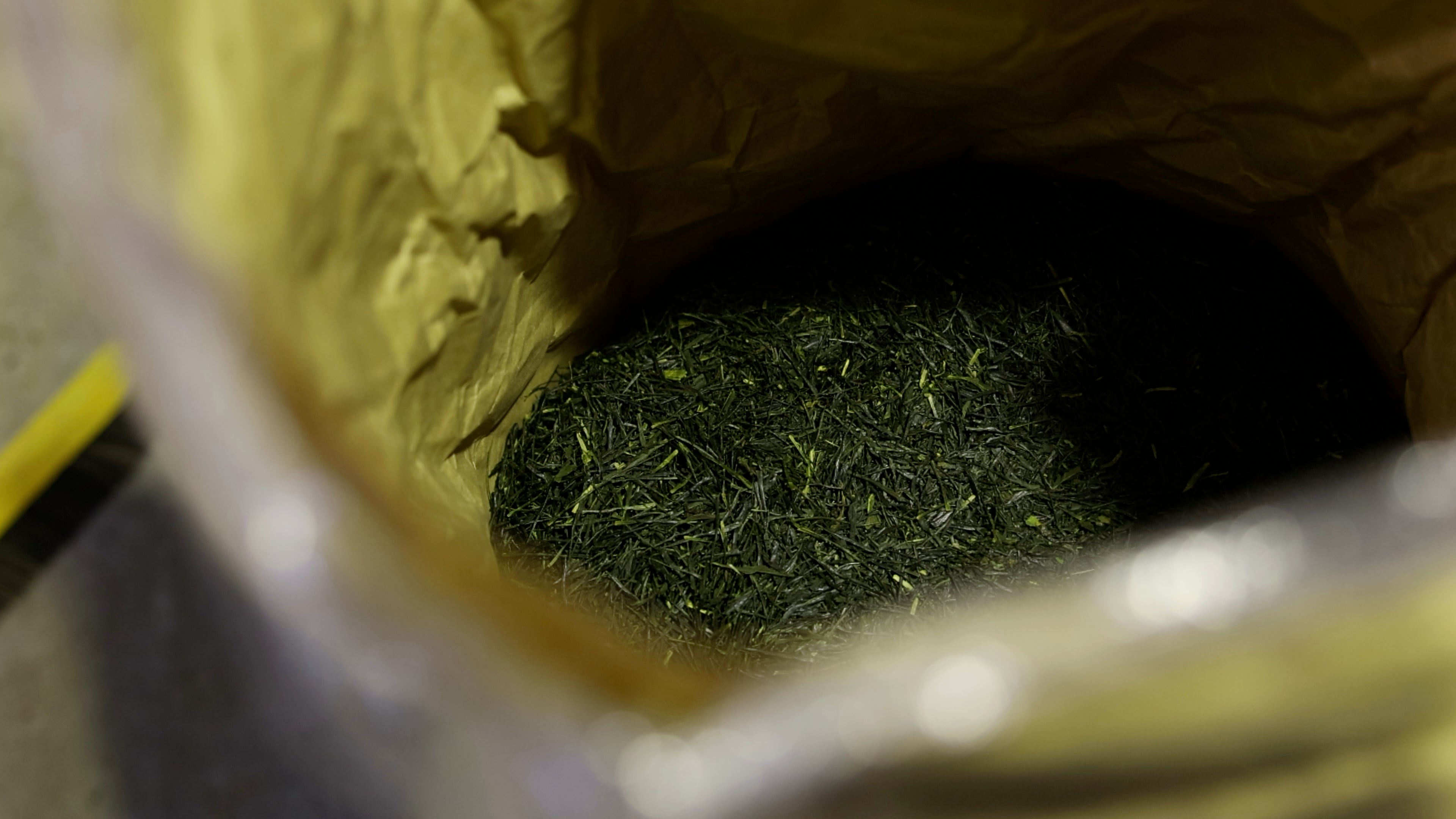 Close-up of processed tea leaves in a paper bag, ready to be packaged and consumed.