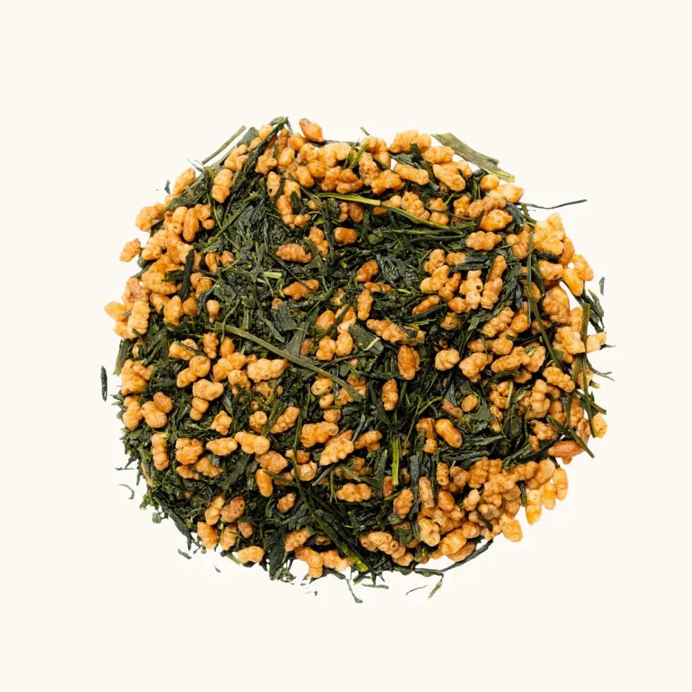 A pile of Japanese green tea leaves and roasted brown rice (Genmaicha), on a beige background
