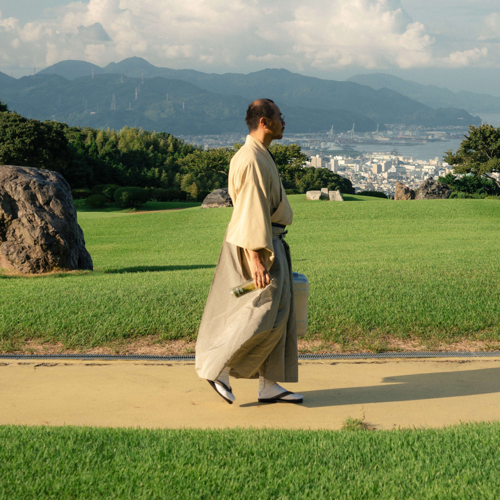 Tea Master Honda Mohei walking, Portable Tea infuser full of Japanese Green Tea (Sencha), walking at the Nippon Daira Hotel, in front of Mt Fuji, covered in clouds.