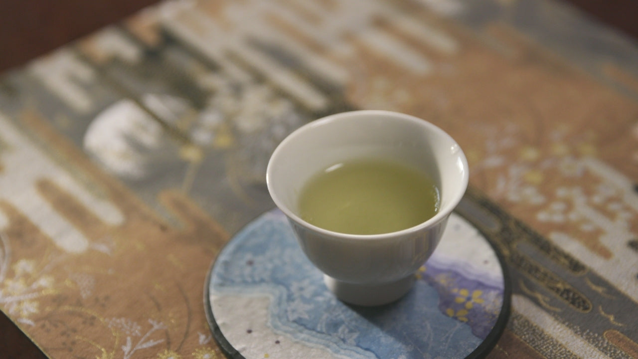 White tea cup with green tea (Shincha) on a textured surface