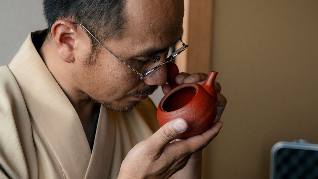 A tea Master in kimono appreciating the aromas and fragrance of a brewed Shincha inside a traditional Japanese Kyusu (teapot).